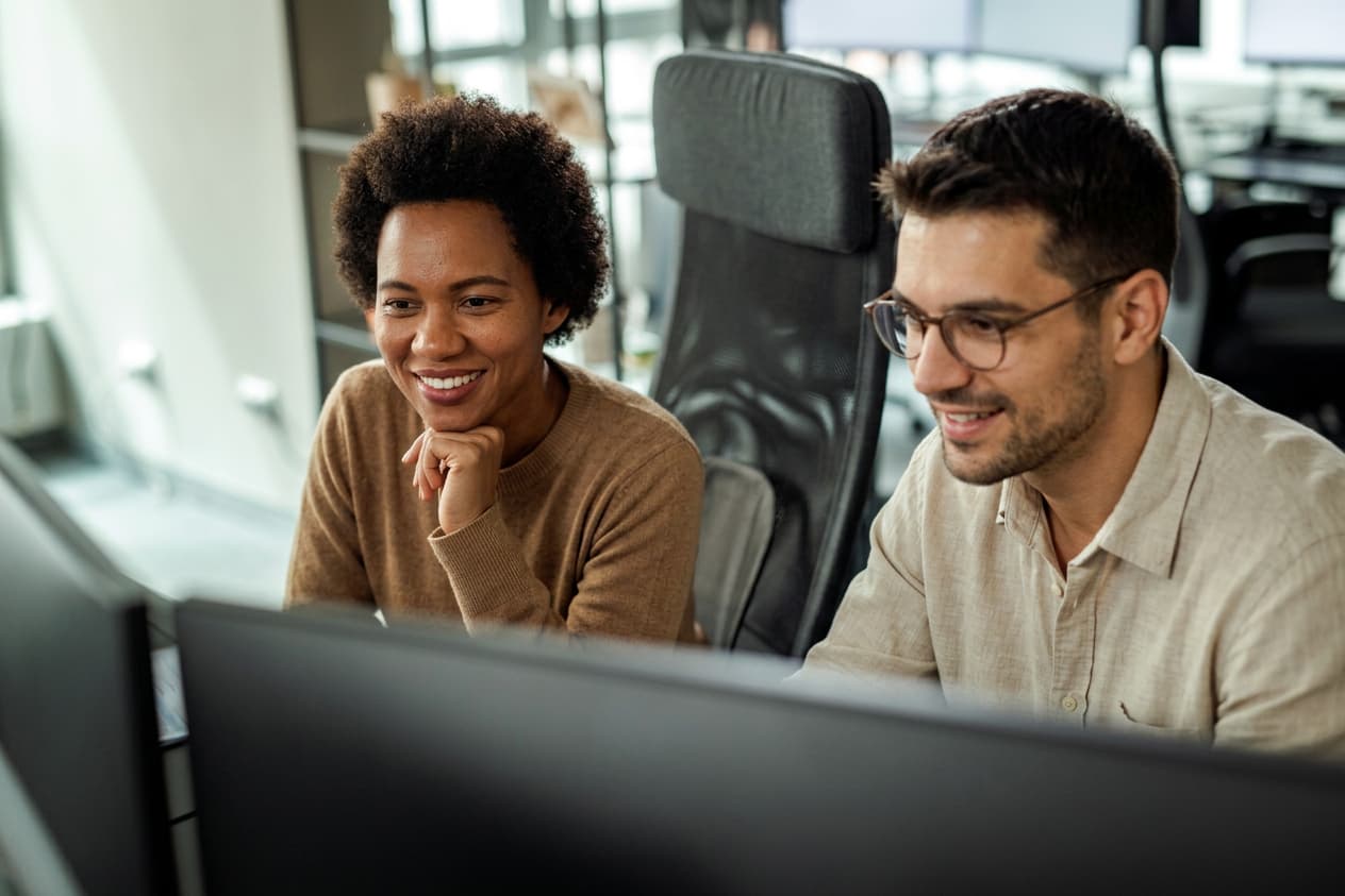 Colleagues collaborating at computers in a modern professional workspace.